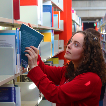 A UCD student browsing books in UCD James Joyce Library.